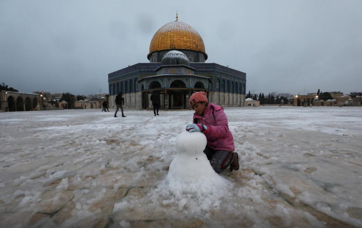 A girl plays by the Dome of the Rock on the compound known to Jews as Temple Mount and to Muslims as Noble Sanctuary during a snowy morning in Jerusalem's Old City, February 18, 2021. - Avaz