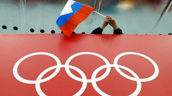 A Russian flag is held above the Olympic Rings at Adler Arena Skating Center during the Winter Olympics in Sochi, Russia on Feb. 18, 2014. - Avaz